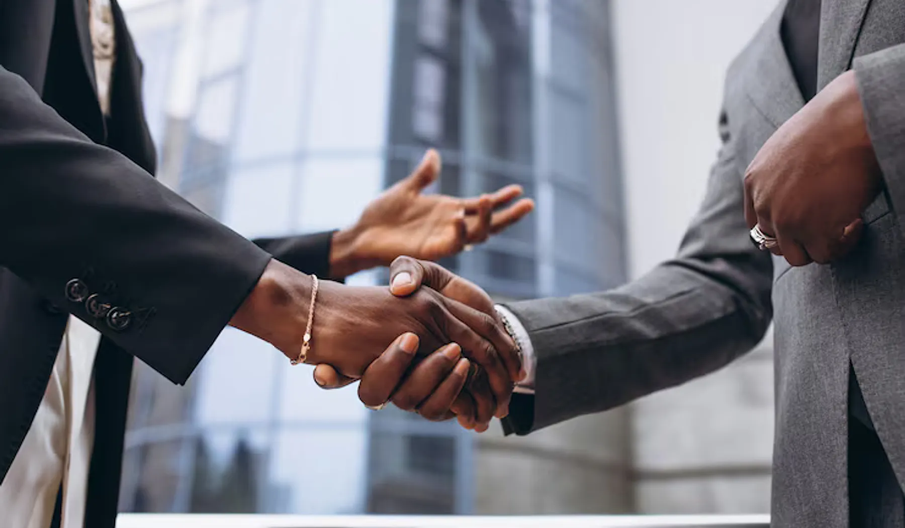 Two professionals shaking hands outside an office building