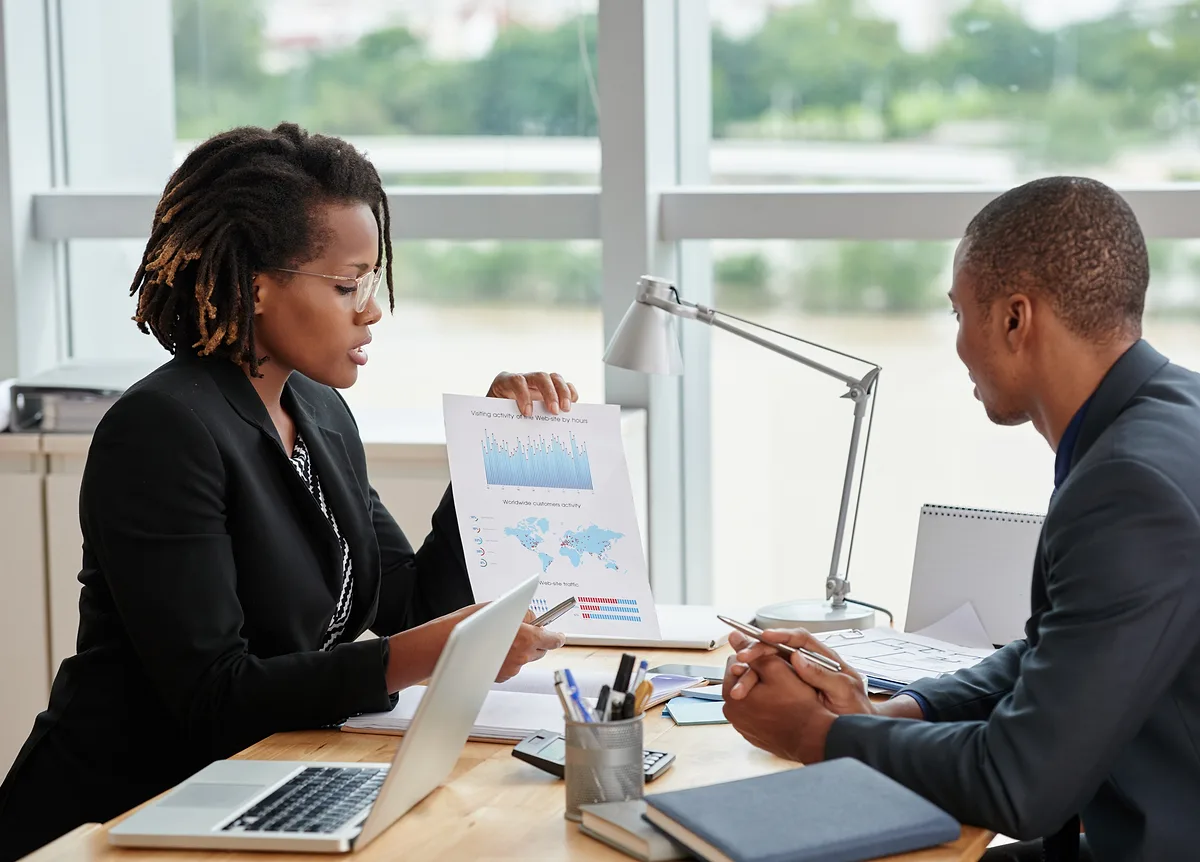 Two advisers reviewing performance charts across a meeting table